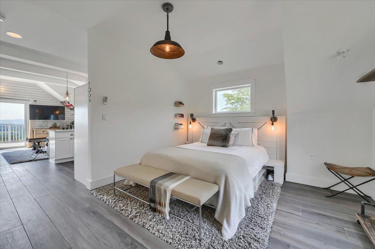 Barn apartment bedroom at The Maple Overlook — king bed, industrial pendant light, valley views, open to living area, private couple suite for intimate weddings upstate New York