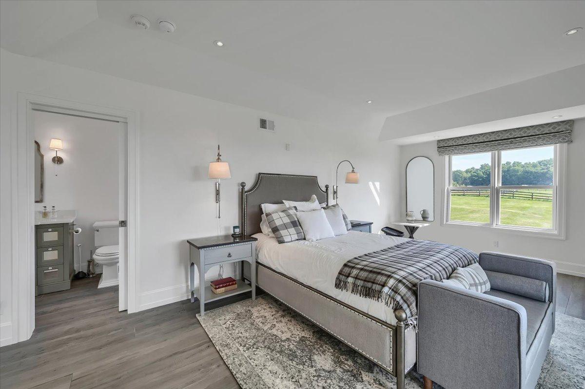 Guest bedroom with en-suite at The Maple Overlook — upholstered queen bed, plaid throw, lawn and paddock views, private en-suite bathroom, luxury upstate New York vacation rental