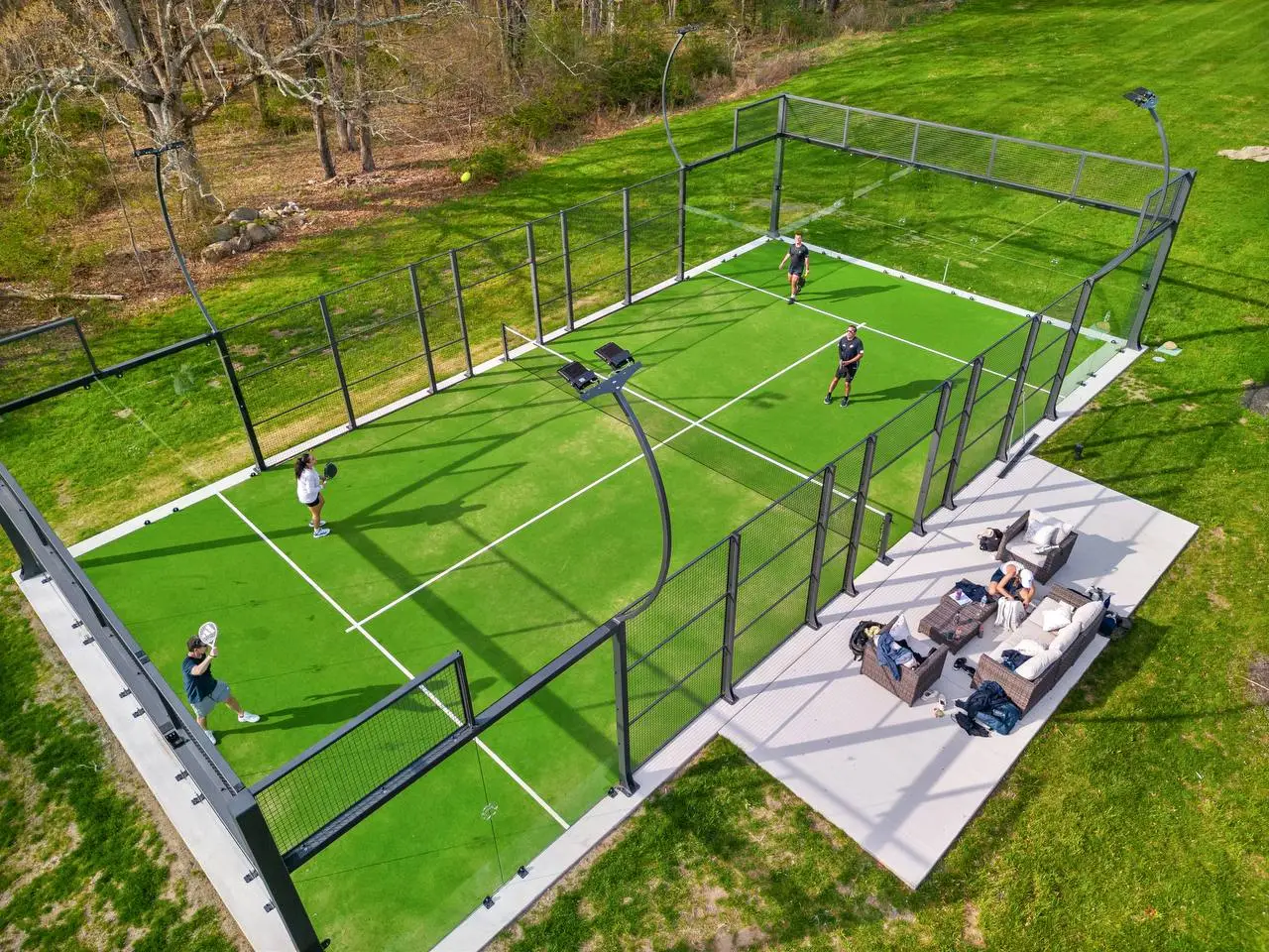 Aerial view of padel court at The Maple Overlook with four players and spectators lounging on the deck — private padel court upstate New York