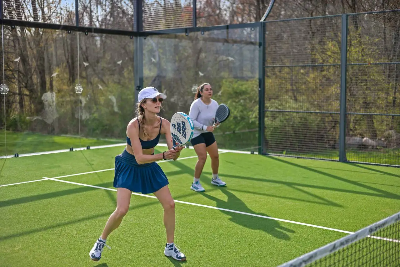Two women playing padel tennis at The Maple Overlook private padel court — outdoor padel venue upstate New York Hudson Valley