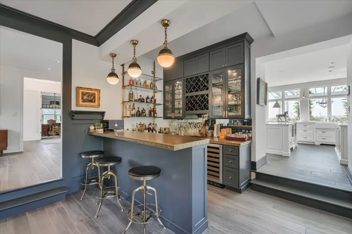 Private bar with dark cabinetry, brass lighting and counter seating