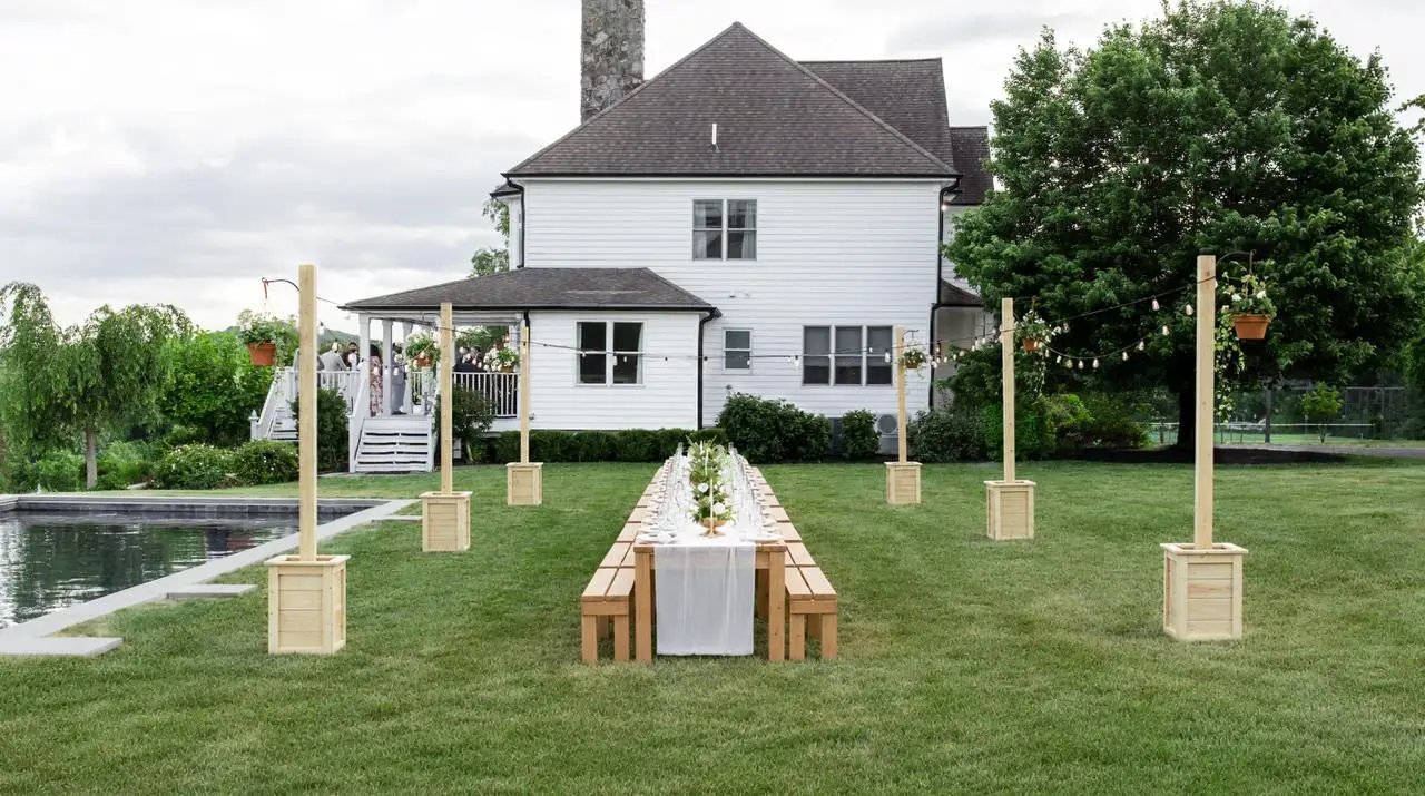 Long farm table outdoor wedding dinner beside the pool at The Maple Overlook — florals, valley views, and estate backdrop